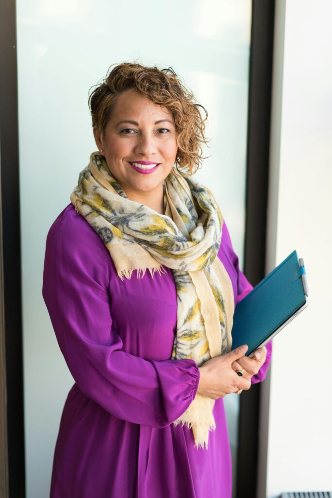 pexels photo 1181424 1181424 Smiling woman in a purple dress and scarf holding a tablet indoors.